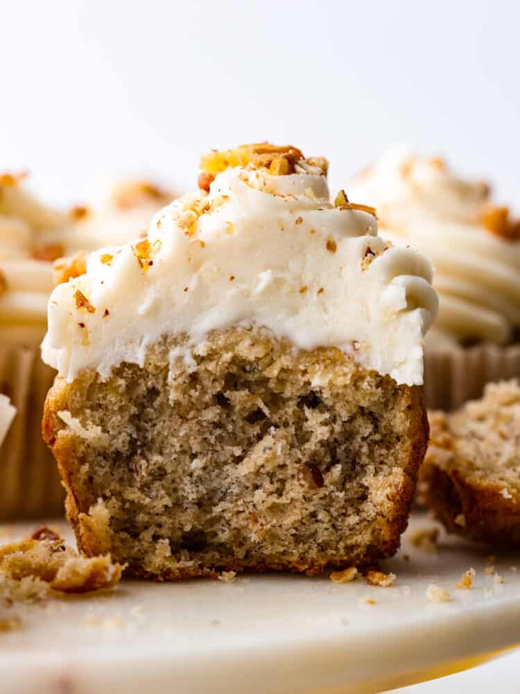 A bite-sized take on a classic Southern dessert, these hummingbird cupcakes are sure to win your heart! Filled with pecans, chopped fruit, and topped with smooth cream cheese frosting, you won't be able to stop at one! Closeup of a cupcake cut in half.