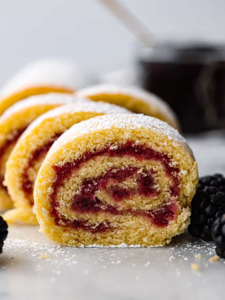 Jelly roll cake is a classic dessert that you need to make at least once! The chiffon cake is rolled with a delicious sweet jelly inside, and all of the flavors scream holiday cheer. You are going to love this easy-to-make dessert that looks stunning on the dinner table! Jelly roll cake cut up and assembled on a plate.