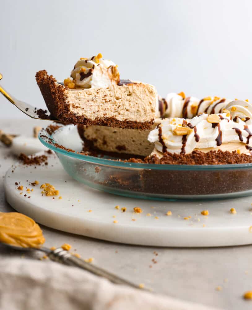No-bake cream cheese peanut butter pie is an easy and amazing no-bake pie! The filling is so creamy and delicious inside a sweet, buttery, chocolate graham cracker crust. This is perfect for your next gathering! A slice of no-bake cream cheese peanut butter pie being served with a cake spatula.