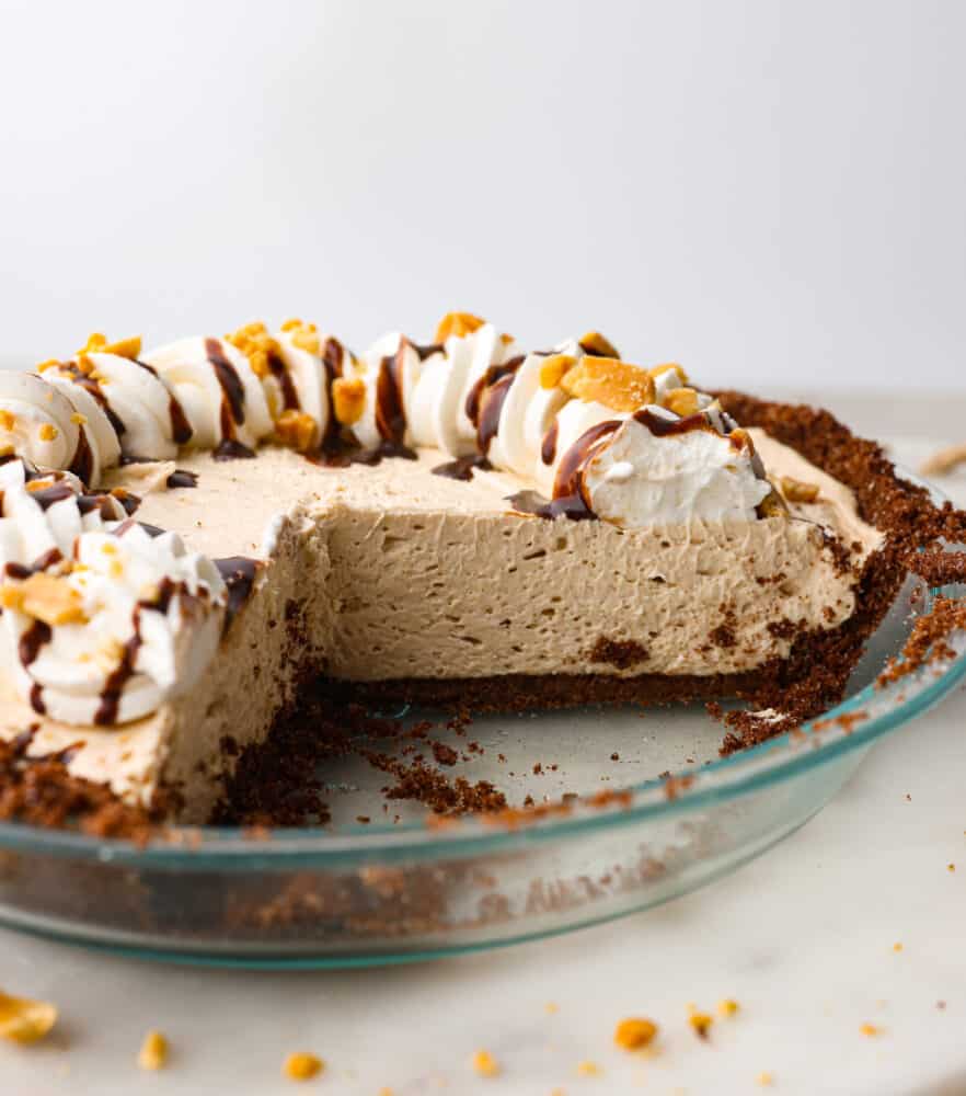 No-bake cream cheese peanut butter pie is an easy and amazing no-bake pie! The filling is so creamy and delicious inside a sweet, buttery, chocolate graham cracker crust. This is perfect for your next gathering! A peanut butter pie with a few slices cut out of it.