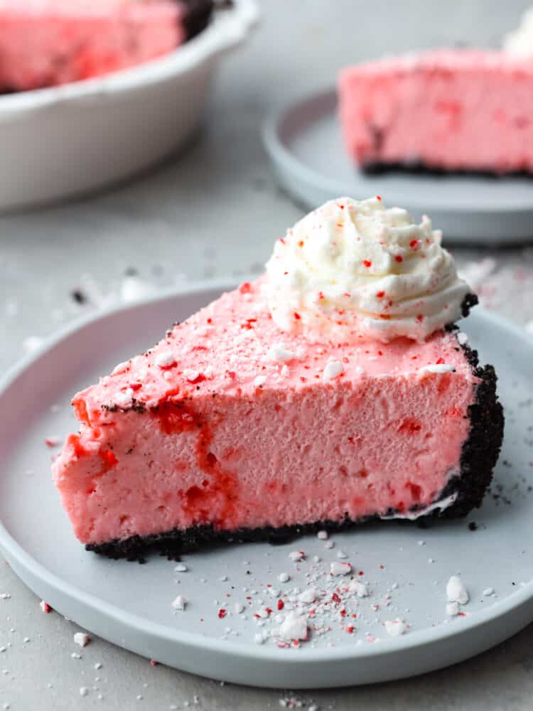 If you are looking for the perfect holiday dessert, then this is it! This Oreo Crust Peppermint Pie has all of the flavors that you want to serve your guests throughout the season. It's creamy and delicious, and you won't be able to stop at one slice! A slice of peppermint pie on a gray plate.