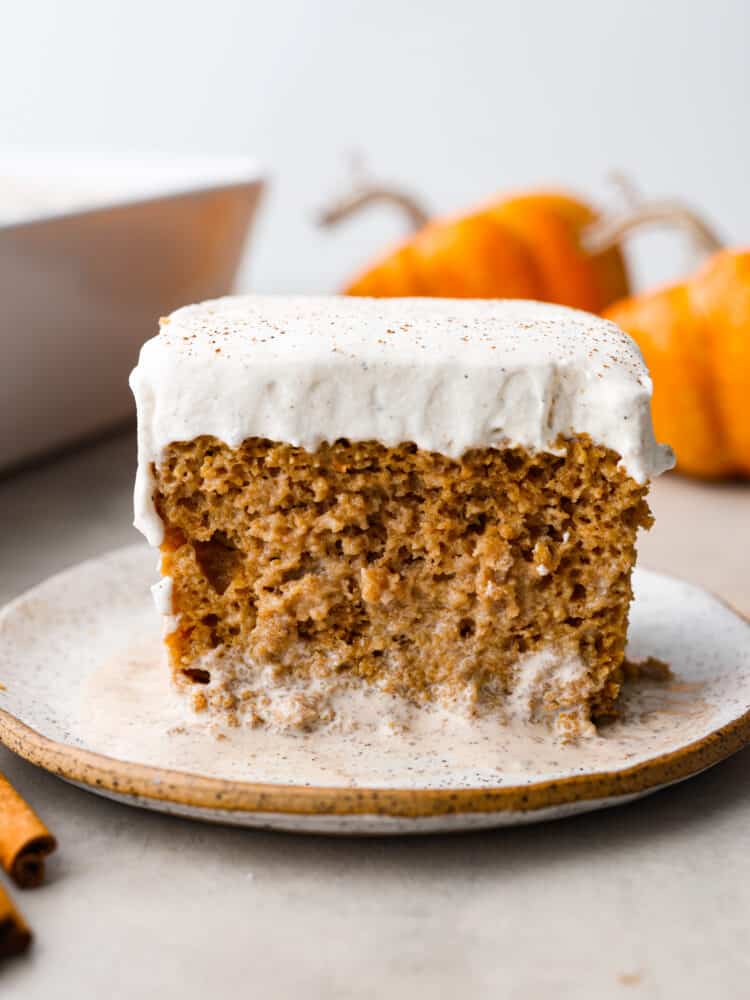 If youโre a fan of traditional tres leches, youโre going to absolutely LOVE this fall version! Soft, moist, and loaded with spiced pumpkin flavor, this pumpkin tres leches is the perfect dessert switch-up for the holidays! Closeup of pumpkin tres leches on a stoneware plate.