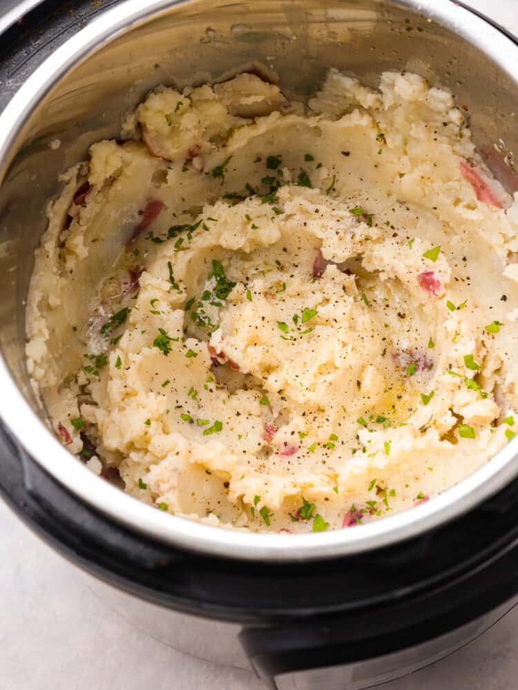 These Instant Pot mashed potatoes are an easy side dish for any holiday or weeknight dinner! They are creamy and flavorful and come together in just 15 minutes. Mashed potatoes in an Instant Pot, seasoned with herbs.