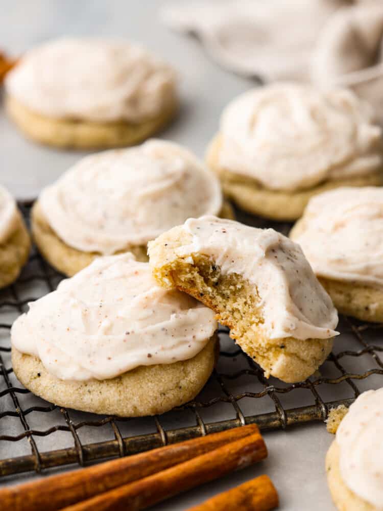 If you love warm Chai spices and soft chewy sugar cookies, this Taylor Swift Chai Cookie recipe is for you! Made popular by T Swift herself, these cookies are everything you're looking for in a fall treat. Get your sweaters on and turn up that Taylor Swift music, you're about to make your new favorite cookie! Taylor Swift Chai cookies sitting on a wire rack, one of them has a bite taken out of it.