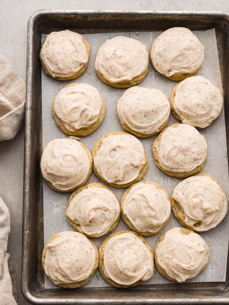 If you love warm Chai spices and soft chewy sugar cookies, this Taylor Swift Chai Cookie recipe is for you! Made popular by T Swift herself, these cookies are everything you're looking for in a fall treat. Get your sweaters on and turn up that Taylor Swift music, you're about to make your new favorite cookie! Frosted Sugar cookies sitting on parchment on a baking sheet.