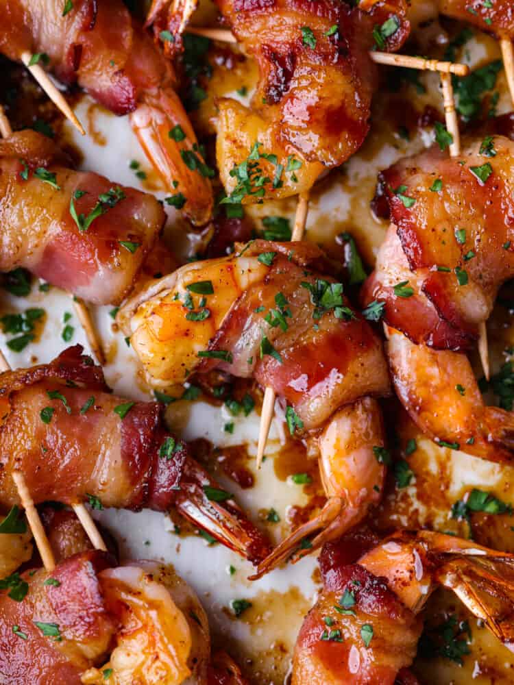 Bacon-wrapped shrimp coated in a sweet and savory glaze and broiled to perfection. The perfect easy appetizer or main course! Closeup of sweet and savory bacon-wrapped shrimp.