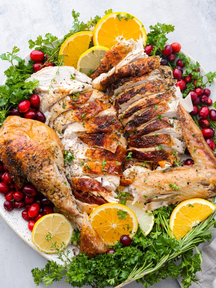 Thanksgiving dinner is made easy with this incredibly moist and perfectly cooked turkey in a bag. The oven-safe roasting bag creates a tender and golden turkey with just a few simple steps making this the BEST way to cook a turkey. Sliced meat styled on a platter with herbs, citrus, and cranberries.