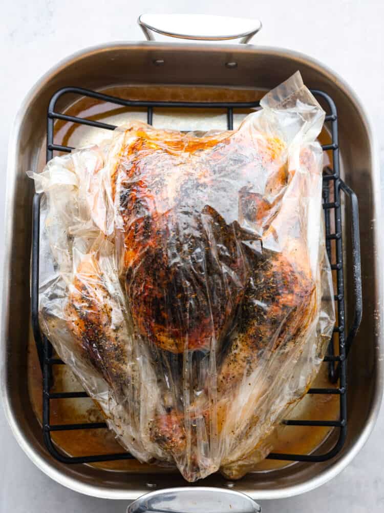 Thanksgiving dinner is made easy with this incredibly moist and perfectly cooked turkey in a bag. The oven-safe roasting bag creates a tender and golden turkey with just a few simple steps making this the BEST way to cook a turkey. Top view of the roasted turkey sitting in the pan.