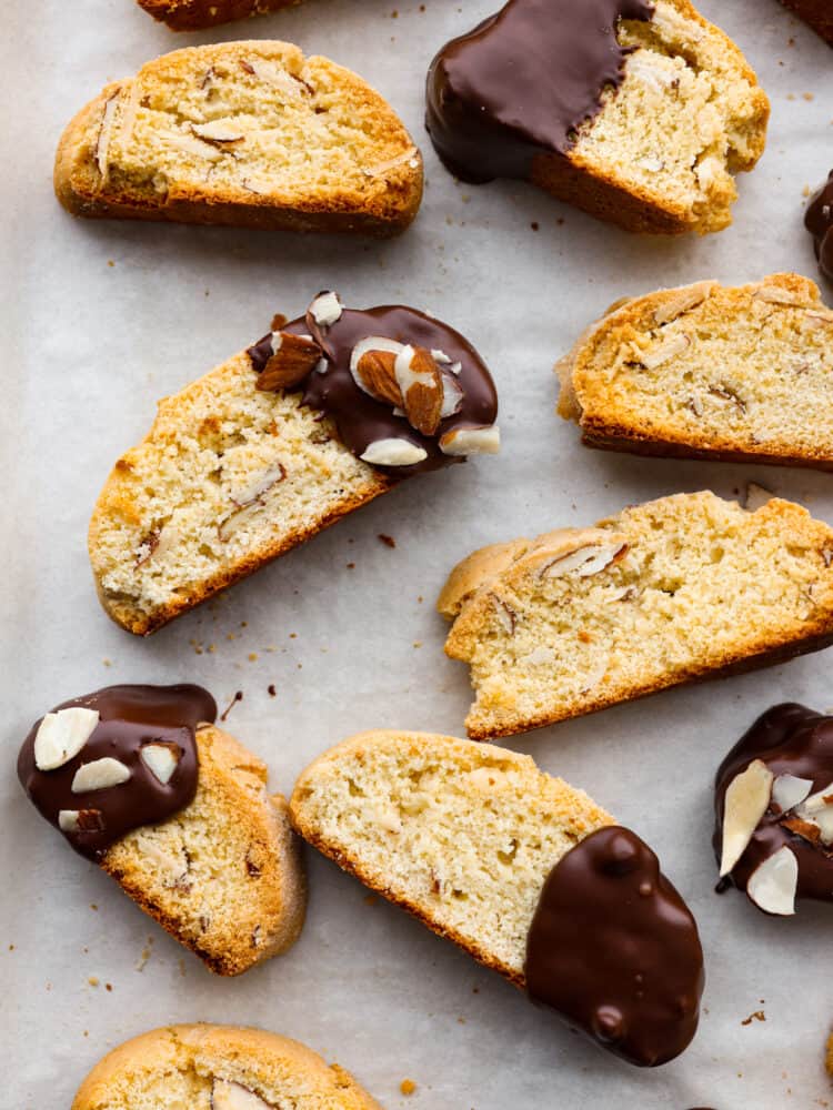 These Classic Biscotti are crispy and crunchy and melt in your mouth with a little help from some hot cocoa or coffee. Dipped in dark chocolate and sprinkled with sliced almonds, this fun treat is perfect for sharing with friends on a cold day! A close up of classic biscotti dipped in chocolate with almonds on top.