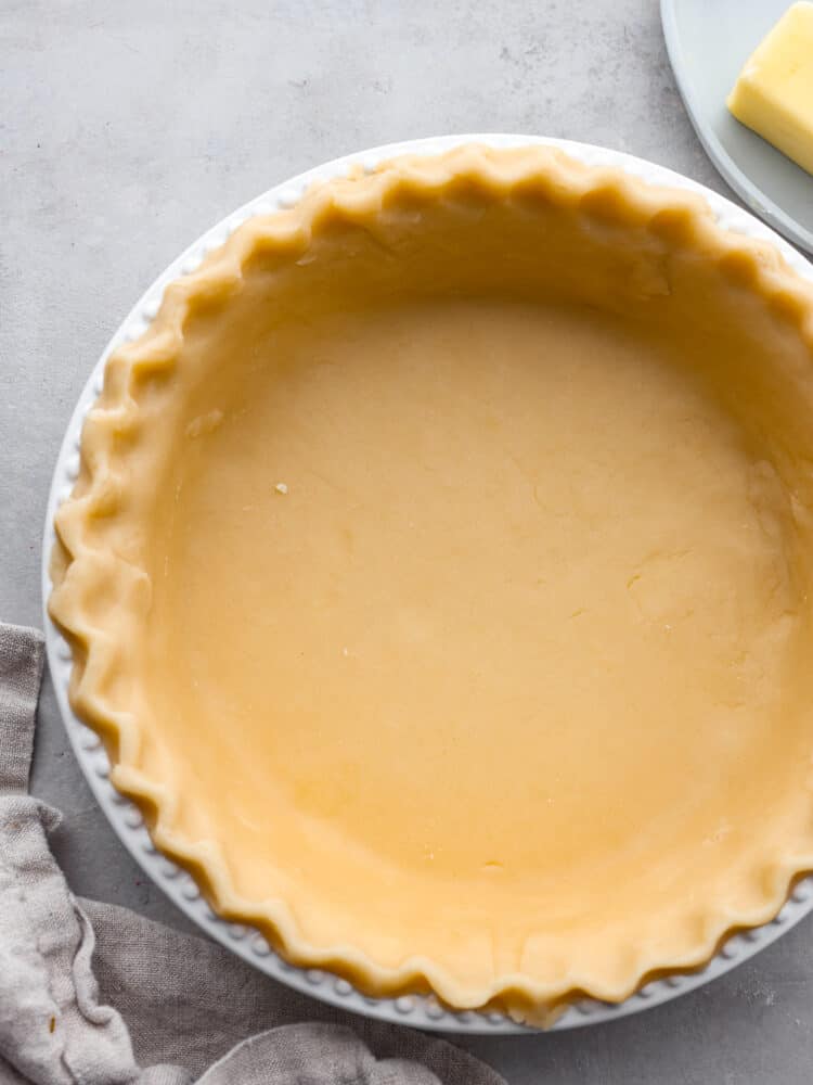 This Butter Pie Crust is the most tender and flaky crust you'll ever make! It's made from just four ingredients and will make the perfect base for all of your pies this holiday season. Butter pie crust in a pie pan unbaked.