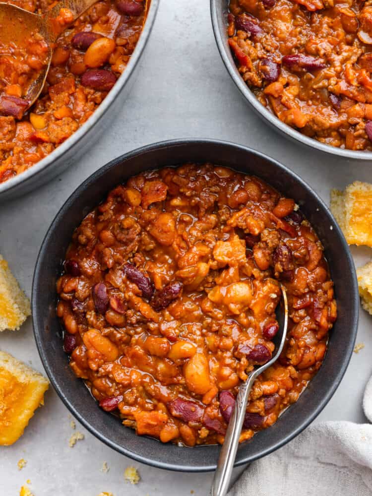 Every time I bring these cowboy beans to a summer BBQ, people start begging for the recipe, and honestly, I donโt blame them. Theyโre hearty, a little smoky, a little sweet, and always the first thing to disappear. Top-down view of baked beans in a black serving bowl.