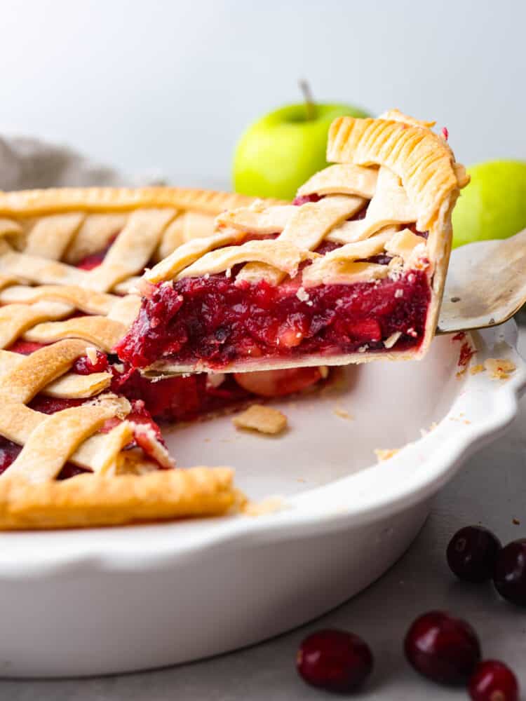 Prepare your Thanksgiving table because this cranberry apple pie is the best addition to the dinner lineup! Itโs delightfully juicy and the best combination of tart and sweet! A slice of cranberry apple pie being served with a cake spatula.