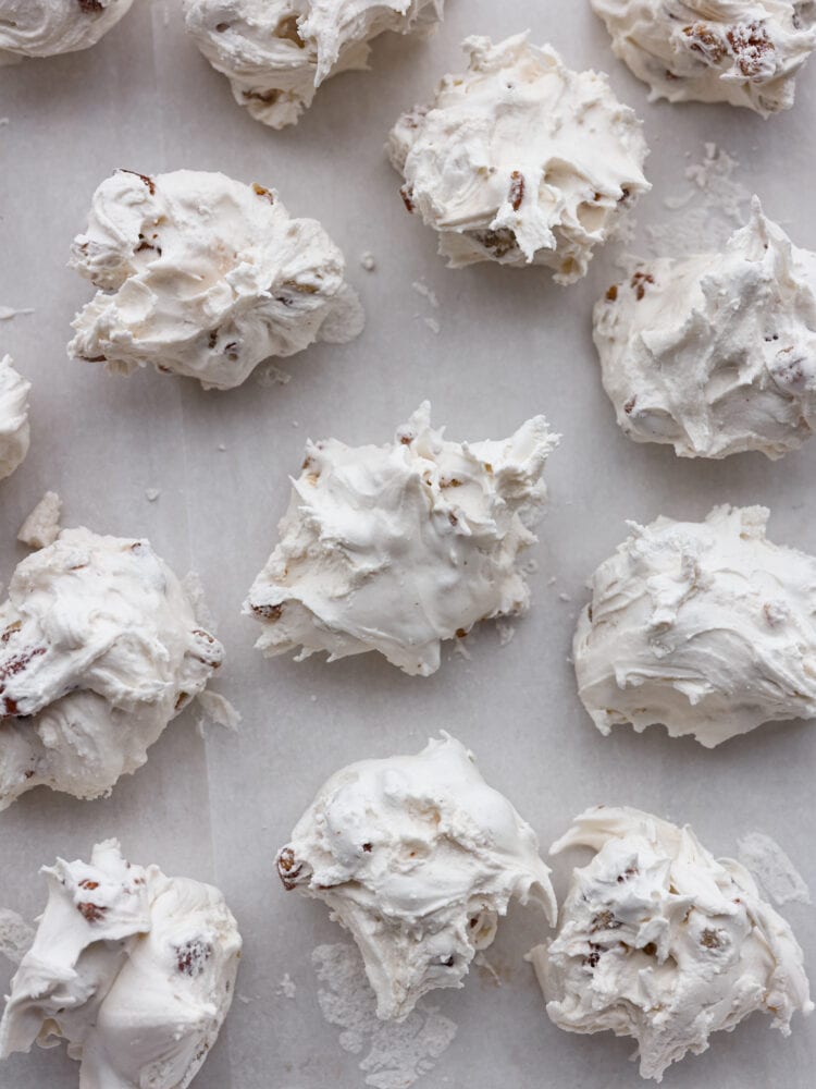 Divinity candy is an old fashioned Southern confection made from egg whites, corn syrup, and sugar. You will love the sweet soft texture of this classic holiday treat that is perfect for sharing with friends and neighbors. Close overhead view of divinity on parchment paper.