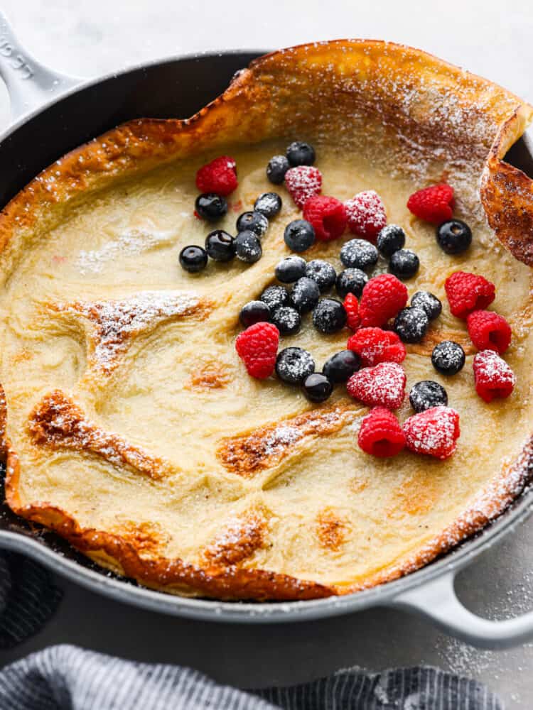 Light, fluffy, and deliciously oversized, this Dutch baby pancake is sure to please at the breakfast table! Add all of your favorite pancake toppings for a tasty treat the whole family will go crazy over. Hero image of a cooked Dutch baby topped with powdered sugar and berries.