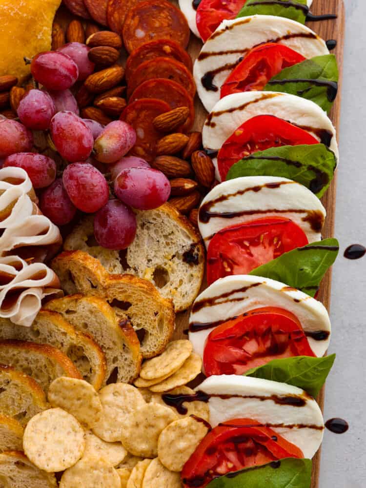 This classic Italian Charcuterie board is the perfect blend of savory and sweet. Loaded with nuts, dried fruit, cured meats, and a Caprese salad, this charcuterie board is perfect for your next get-together! A close up on the caprese salad and crostini.