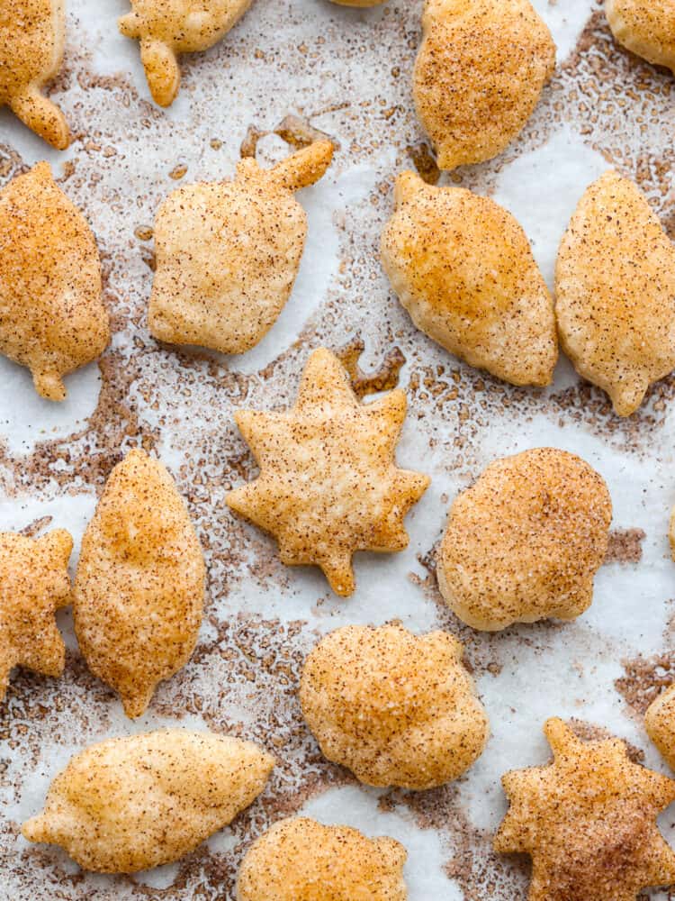 Turn leftover pie crust into perfect buttery and flakey pie crust cookies. Roll and shape using fun cookie cutters then simply sprinkle with sweet cinnamon and sugar.ย Top view of pie crust cookies on parchment paper.