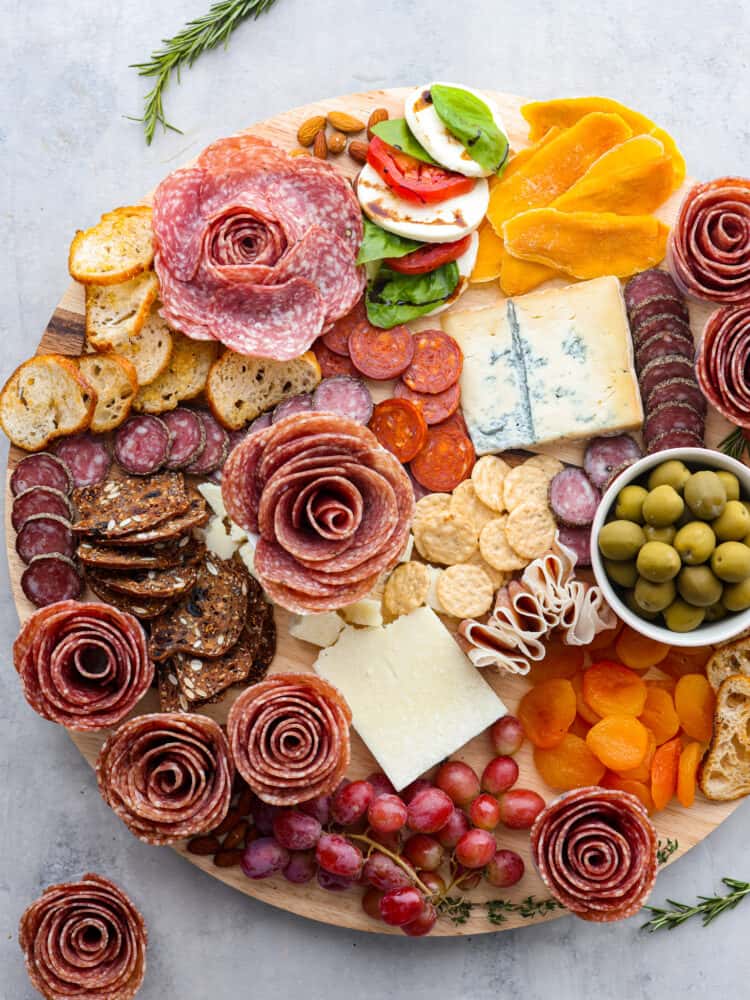 A salami rose is the perfect way to dress up your charcuterie board. This recipe will show you how to make a salami rose in two different ways that will be fun to put together and really wow your guests! A charcuterie board with salami roses and an assortment of meats, cheeses, fruits and veggies.