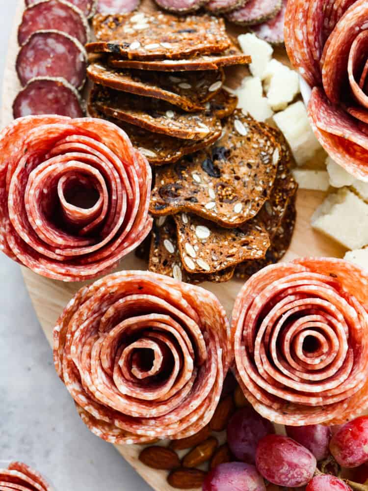 A salami rose is the perfect way to dress up your charcuterie board. This recipe will show you how to make a salami rose in two different ways that will be fun to put together and really wow your guests! A close up of a charcuterie board with salami and crackers and cheese.