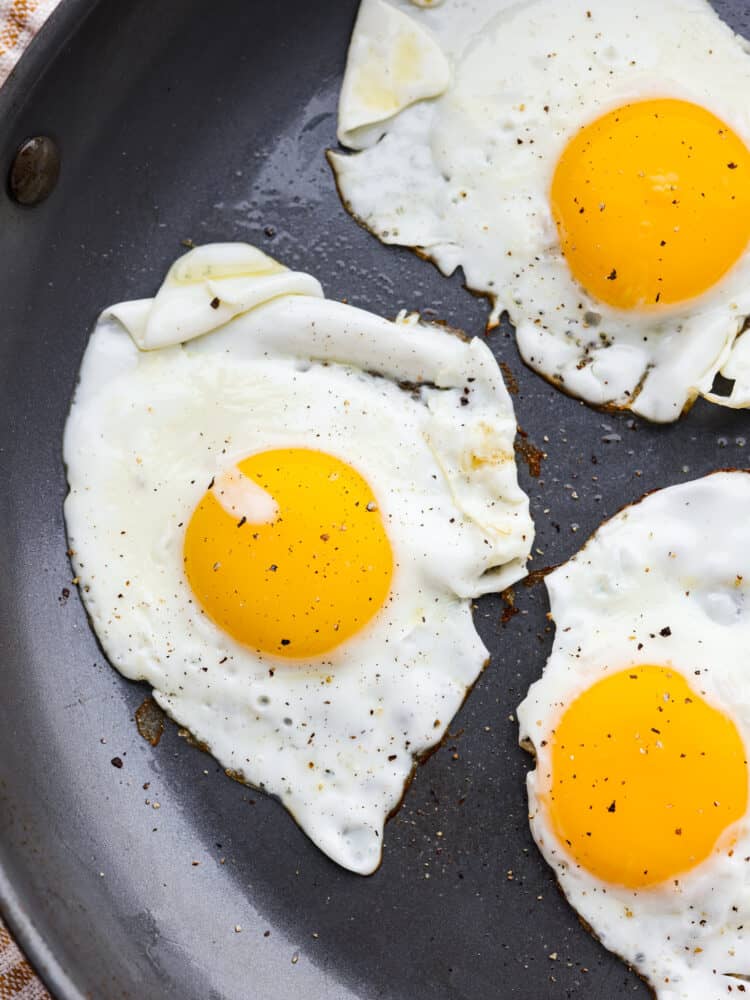 A Sunny Side Up Egg is a perfect way to add protein to a meal, and is a must-have skill in the kitchen! The key is timing and temperature, and following my simple tips you'll whip up the most flavorful and perfectly runny pan-fried egg. A close up of sunny side up eggs cooked in a frying pan.