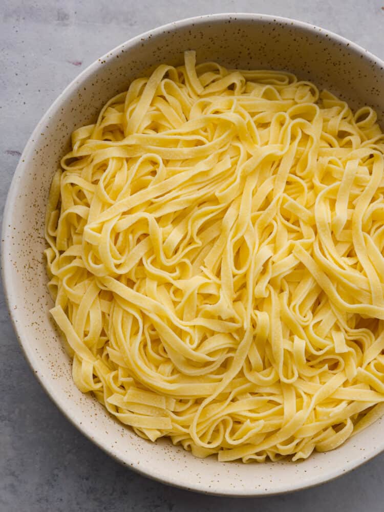 Tagliatelle pasta is thick, soft, and perfect for all of your homemade sauces! Here's how to cook it perfectly every time! Top-down view of cooked tagliatelle in a spotted bowl.