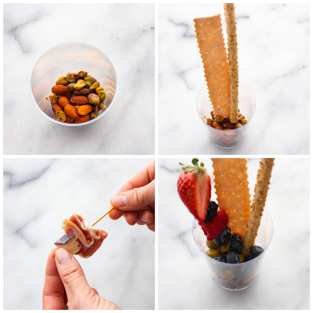 Impress your guests with these quick and easy charcuterie cups! They’re packed with an assortment of meats, cheeses, fruit and nuts; it’s the ultimate finger food! 4-photo collage of pistachios and almonds being added to plastic cups and then fruit and meat skewers added in.