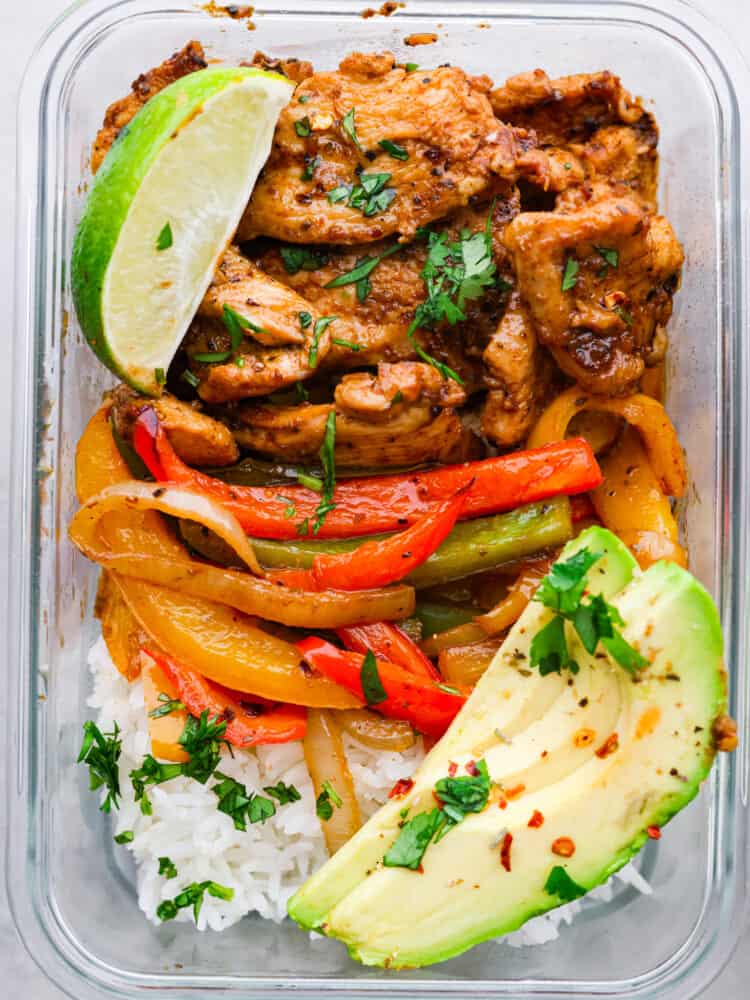 Whether you are trying to stick to a diet, eat out less, or just stop stressing about what to make for dinner, these Chicken Fajita Meal Prep Bowls are your answer! This recipe makes a flavorful and filling meal that is ready to go for the perfect work lunch or quick dinner. A close up on the chicken fajita meal prep bowl with a fresh lime and avocado.