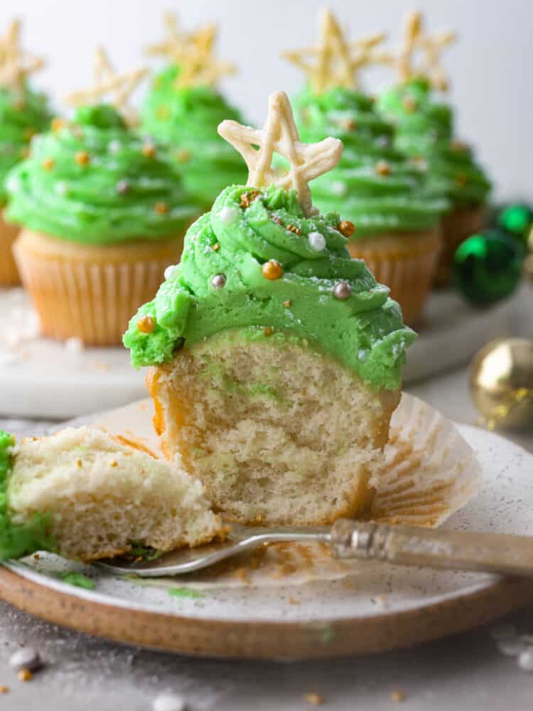 If you're looking for a dessert that is absolutely delicious but also looks great on the holiday dinner table, these Christmas tree cupcakes are it! Moist vanilla cupcakes topped with homemade buttercream frosting that almost look too good to eat! Front view of a cupcake cut in half.