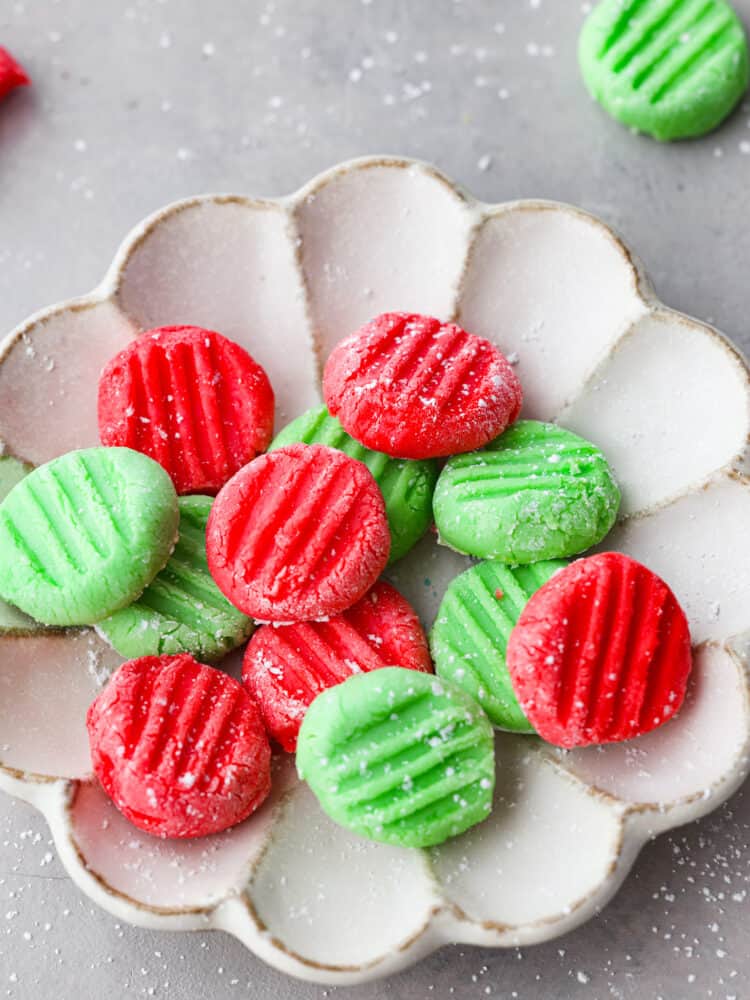 This classic and timeless Cream Cheese Mint is the perfect melt-in-your-mouth candy to make for your next party. They are creamy and sweet with a hint of mint flavor that is so refreshing, you'll want to eat them again and again! A close up of the red and green mints in a scalloped dish.