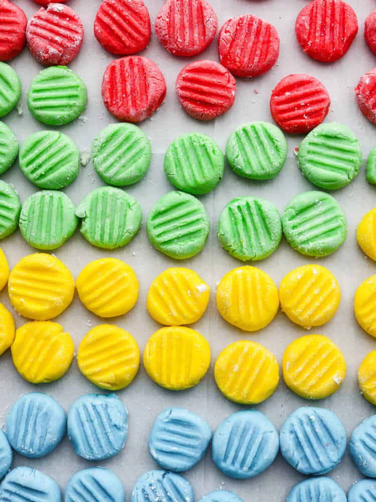 This classic and timeless Cream Cheese Mint is the perfect melt-in-your-mouth candy to make for your next party. They are creamy and sweet with a hint of mint flavor that is so refreshing, you'll want to eat them again and again! Cream cheese mints in red, green, yellow, and blue all lined up on a parchment paper.
