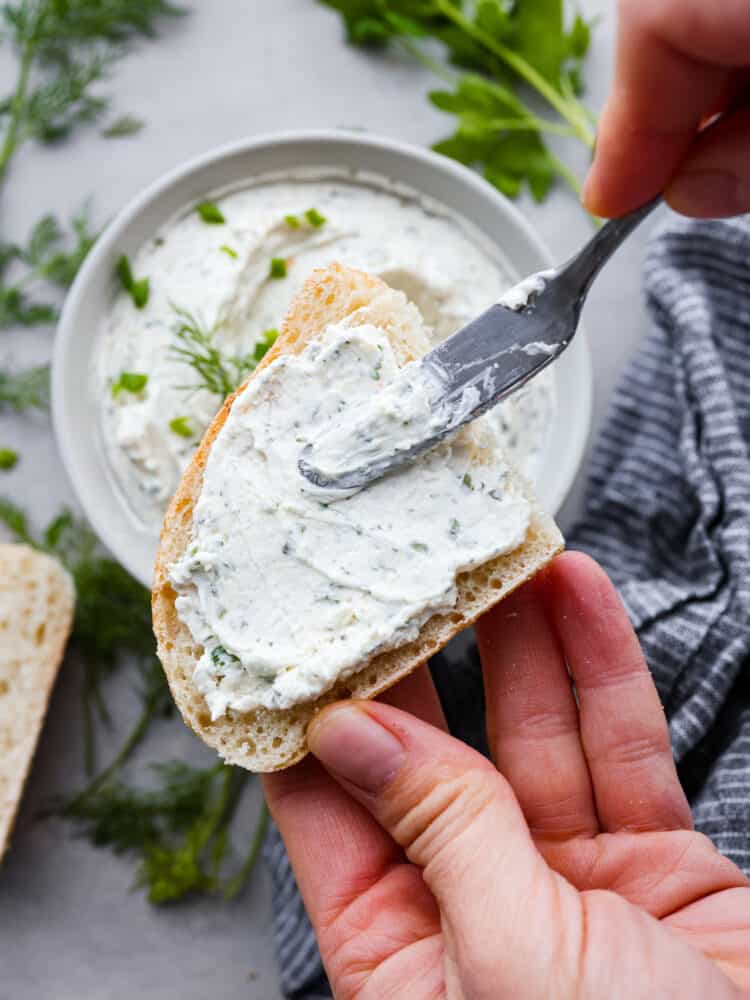 Garlic herb cream cheese is tangy and full of flavor. It's the perfect spread for bagels or served as an appetizer with fresh veggies or crackers. It takes 10 minutes to whip up and will be the hit of your next party! Cream cheese spread over the top of bread.