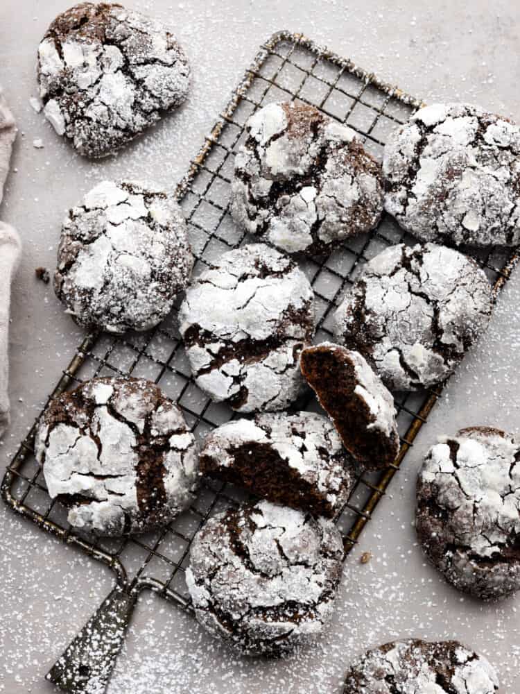 Chocolate crinkle cookies are classic chocolate cookies with a decadent chewy texture. The crinkle top on these rich fudgy cookies have a sweet sugar coating making them everyone's favorite holiday cookie! Overhead view of cookies on a cooling rack and dusted with powdered sugar.