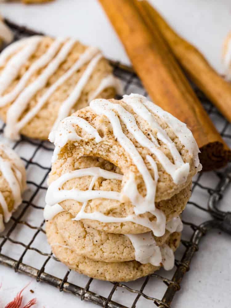 These eggnog cookies are soft, chewy, and beautifully flavored with hints of cinnamon and nutmeg. They are going to become fast favorites with their heavenly eggnog glaze! Closeup of eggnog cookies stacked on top of each other. One has a bite taken out of it.