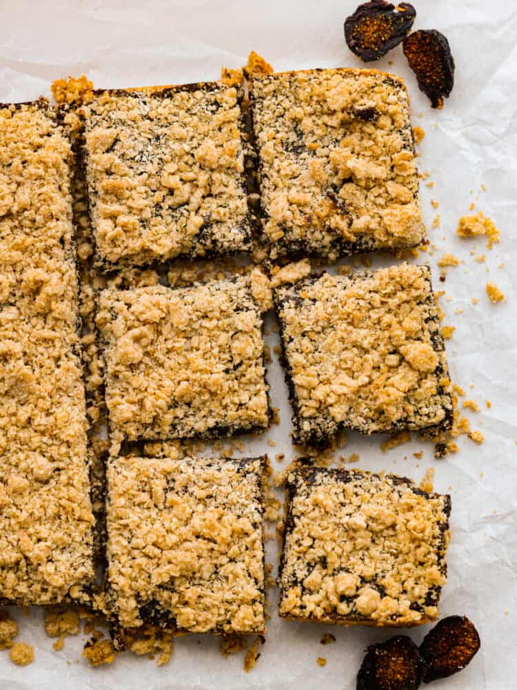 So much better than store bought and so fun to make, these oatmeal fig bars are sweet and salty and everything you hope they would be! The sticky fig jam is sandwiched between two delicious layers of oatmeal crumble and crust. You really can't beat this sweet treat! Oatmeal fig bars lined up on parchment paper and cut into squares.