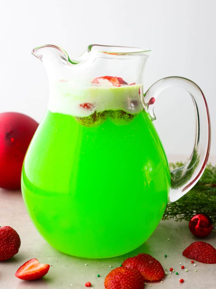 Grinch punch is a fun and festive drink for the holidays that comes together with just 4 ingredients! This tasty drink is bursting with lime and strawberry flavor. It's the perfect addition to any Christmas meal! Green punch in a large glass pitcher.