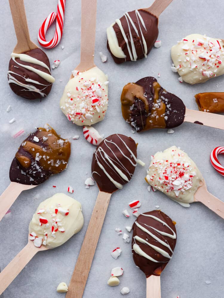 These quick and easy hot chocolate spoons are the BEST! Not only are they adorable and the perfect holiday gift, but they make a knockout cup of hot cocoa! Various hot chocolate spoons laid out on parchment paper.