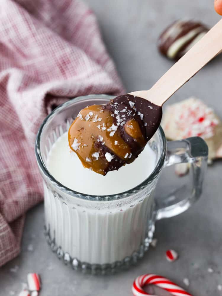 These quick and easy hot chocolate spoons are the BEST! Not only are they adorable and the perfect holiday gift, but they make a knockout cup of hot cocoa! A hot chocolate spoon hovering above milk in a glass mug.