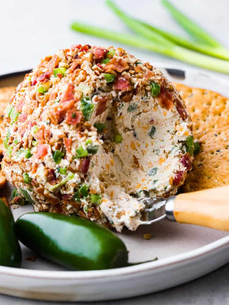 This jalapeno bacon cheese ball is perfectly creamy, rolled in crunchy bacon, and topped off with green onions and salty pecans. It's the perfect holiday appetizer and filled with SO much flavor! Hero image of a jalapeno bacon cheese ball.
