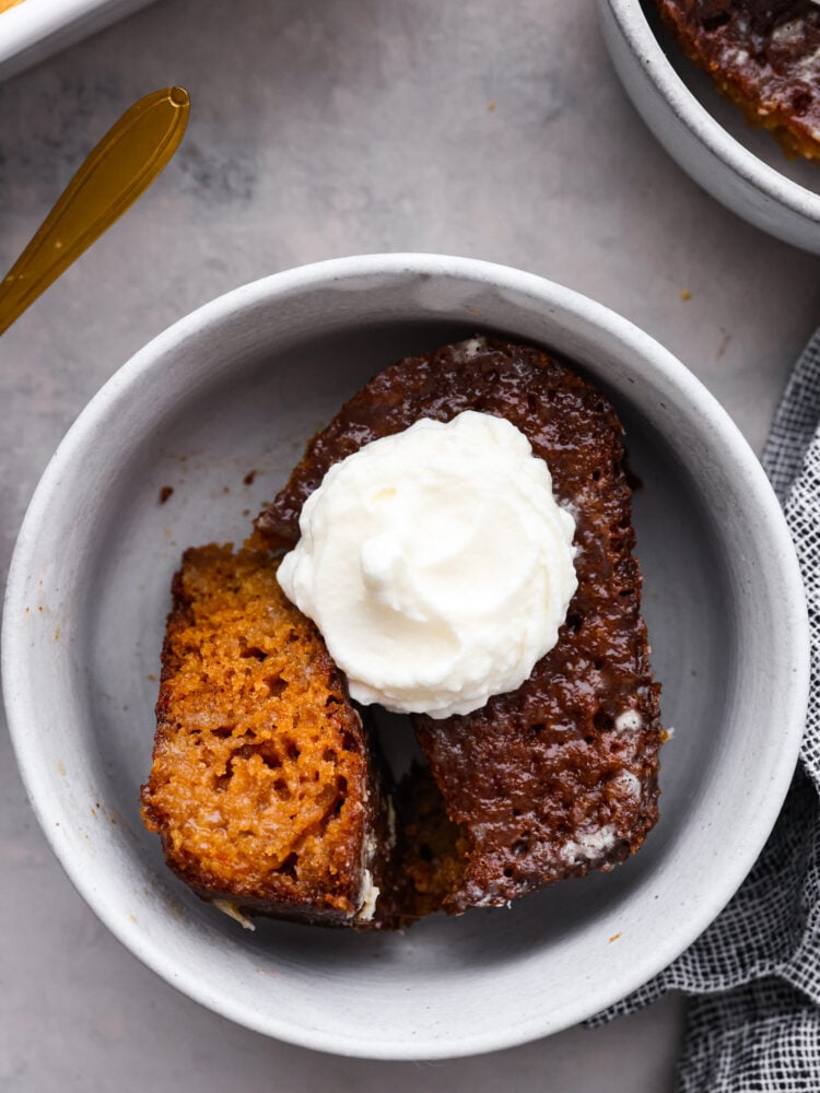 Malva pudding is a delicious cake-like dessert with an amazing caramelized outer layer. Itโs extra moist, soft, and bursting with apricot flavor. Closeup of malva pudding in a white bowl.