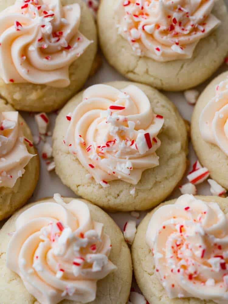These peppermint meltaways literally melt in your mouth with each and every bite. The combination of butter, powdered sugar, and cornstarch creates a fluffy and delicious cookie that everyone will LOVE! Close up view of peppermint meltaways with frosting and sprinkled peppermint candy on top.
