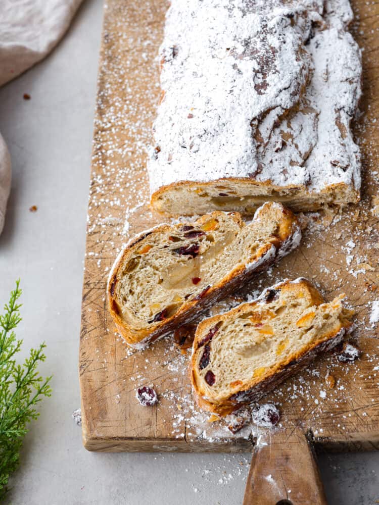 This traditional German stollen bread is the perfect treat for the holidays! It's a delicious sweet bread filled with cranberries, raisins, candied citrus, and a luscious almond filling. Top-down view of stollen, sliced into 2 pieces.