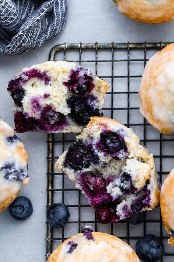 These blueberry muffins with a sugared glaze are so good, they should be illegal! Soft, buttery, and bursting with sweet blueberry flavor, they're the perfect excuse to have dessert for breakfast. Top-down view of a blueberry muffin cut in half.