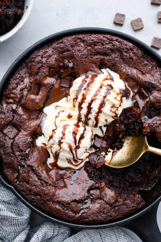 This easy skillet brownie is just the chocolatey, ooey-gooey dessert you need in your life! Top it off with a scoop of vanilla ice cream for the ultimate indulgent treat you can enjoy straight from the pan! Brownies cooked in a skillet, topped with vanilla ice cream.