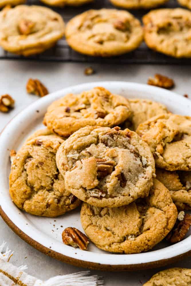 Soft, chewy,ย butter pecan cookiesย made with lightly toasted pecans andย crunchy toffee bits. These are buttery and delicious and there's no mixer or chilling required! Butter pecan cookies in a white plate.