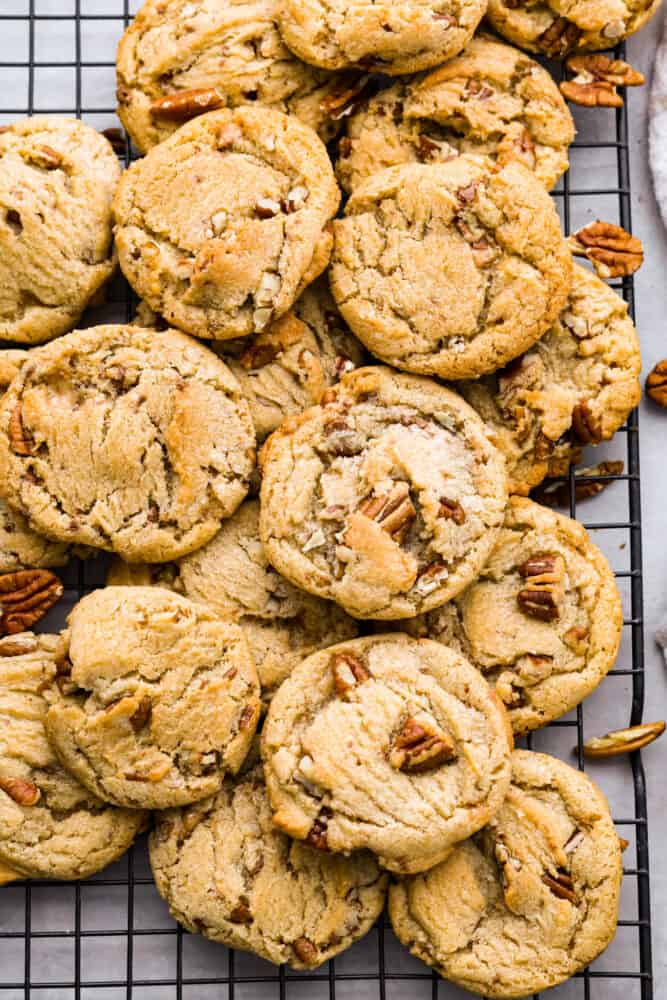 Soft, chewy,ย butter pecan cookiesย made with lightly toasted pecans andย crunchy toffee bits. These are buttery and delicious and there's no mixer or chilling required! Top-down view of butter pecan cookies on a cooling rack.