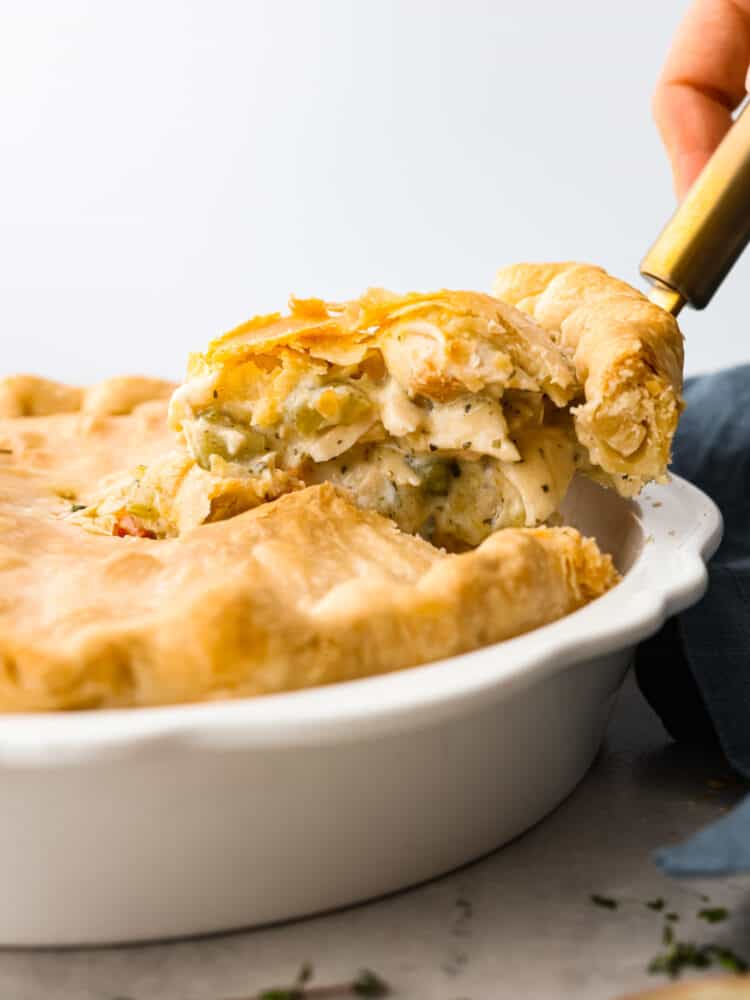 There is nothing more comforting than this absolutely perfect chicken pot pie! A flaky pie crust filled with chicken, veggies, and tons of flavor is just what you need on a cold winter day, or any day. This is a classic recipe you will definitely want in your recipe book! A slice being lifted out of the pie dish with a spatula.
