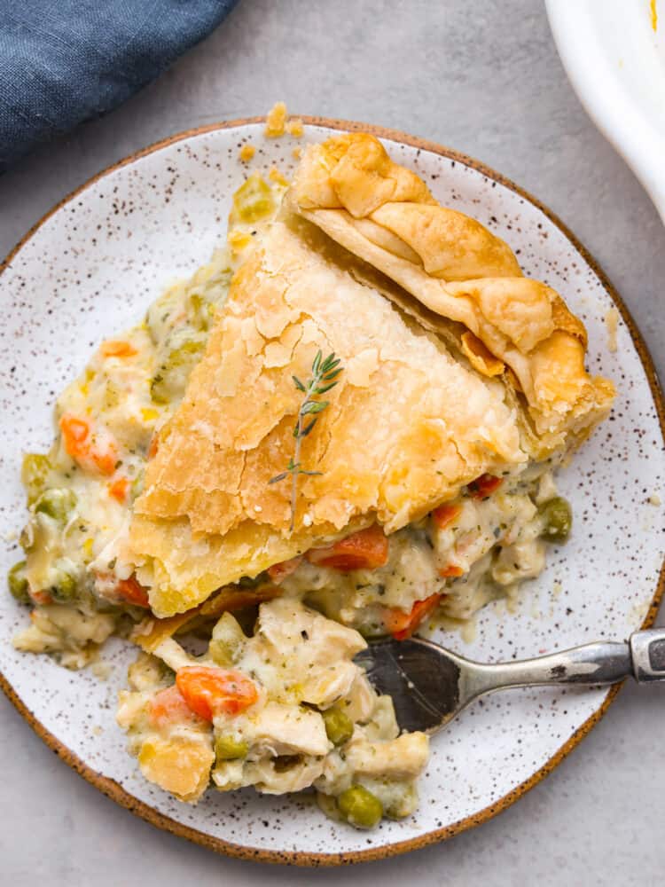 There is nothing more comforting than this absolutely perfect chicken pot pie! A flaky pie crust filled with chicken, veggies, and tons of flavor is just what you need on a cold winter day, or any day. This is a classic recipe you will definitely want in your recipe book! A slice of chicken pot pie on a plate with some on a fork.