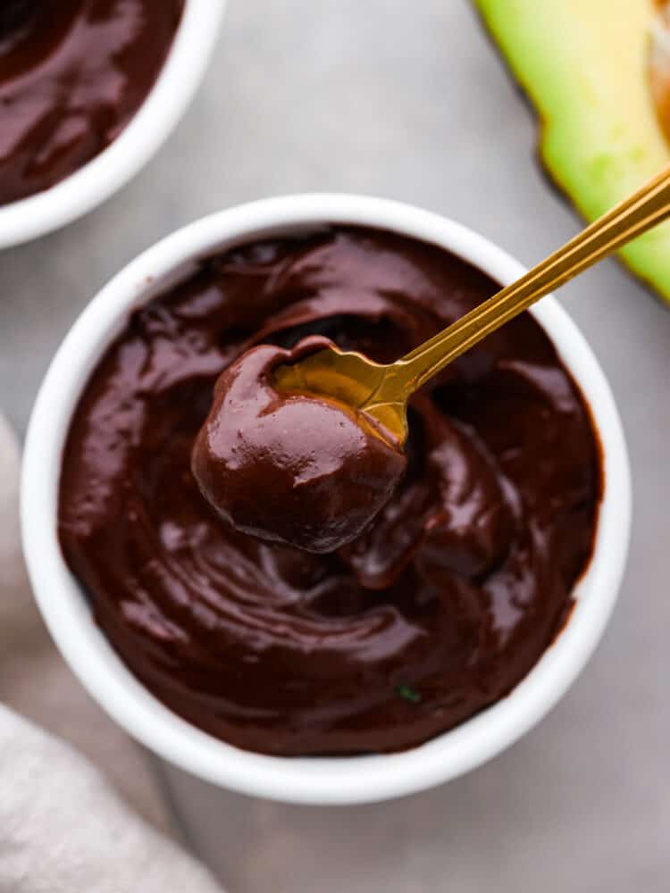 Avocado chocolate pudding is a creamy and dark dairy free chocolate pudding with fresh and good-for-you ingredients! Not only does it taste better than regular pudding, but it's as easy as putting all of the ingredients in the blender to curb your sweet tooth without all the guilt. A close up on the pudding with a golden spoon.