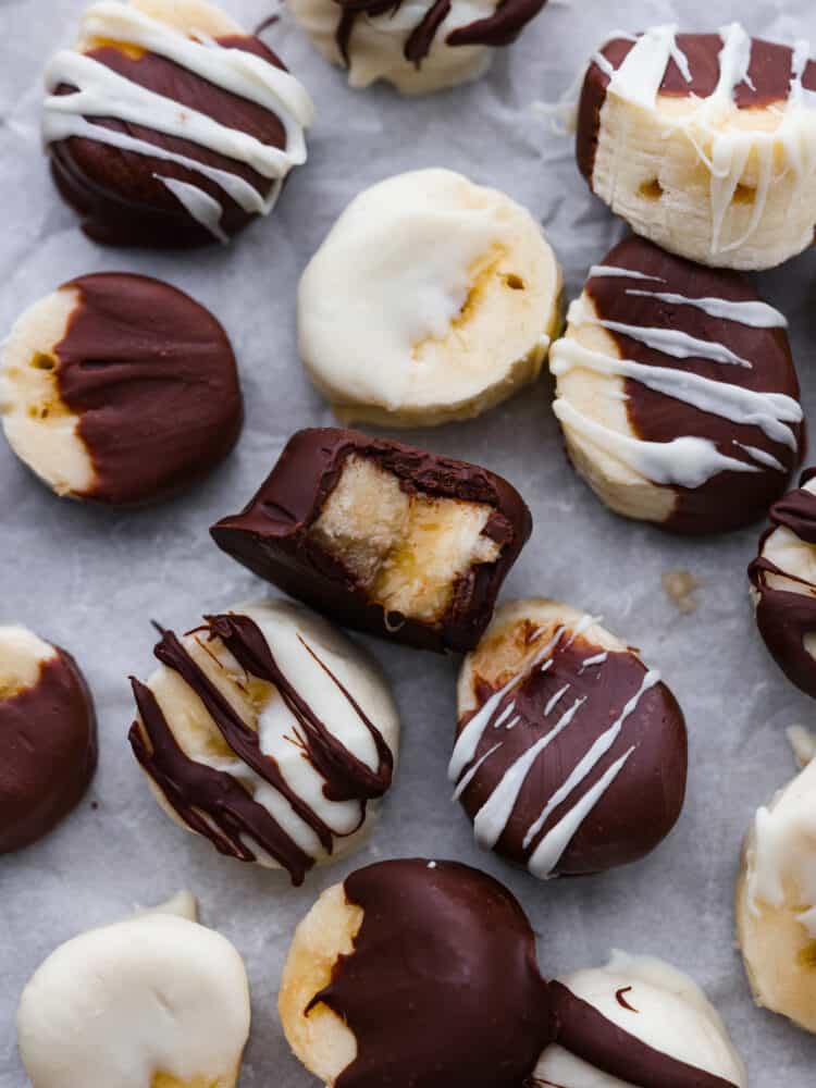 Prepare your tastebuds for these luscious chocolate covered bananas! With just a few simple ingredients, you'll be whipping up a creamy, chocolatey treat that's sure to bring a smile to your face. Hero image of chocolate covered banana slices on parchment paper.