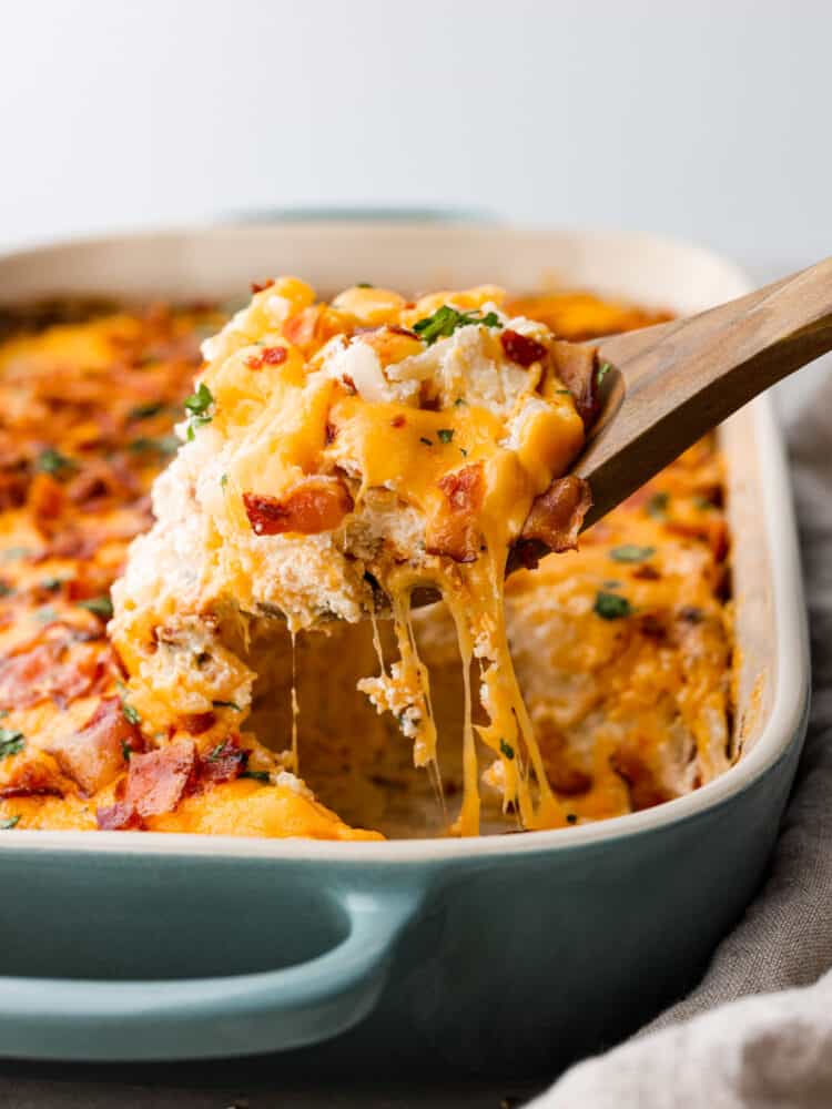 Just like the name says, these crack potatoes are so good you’ll be addicted! It’s an easy, cheesy side dish that the whole family will love. Shredded potatoes covered in a cheesy ranch sauce topped with bacon. What could be better? Hero image of crack potatoes being scooped out of the pan.