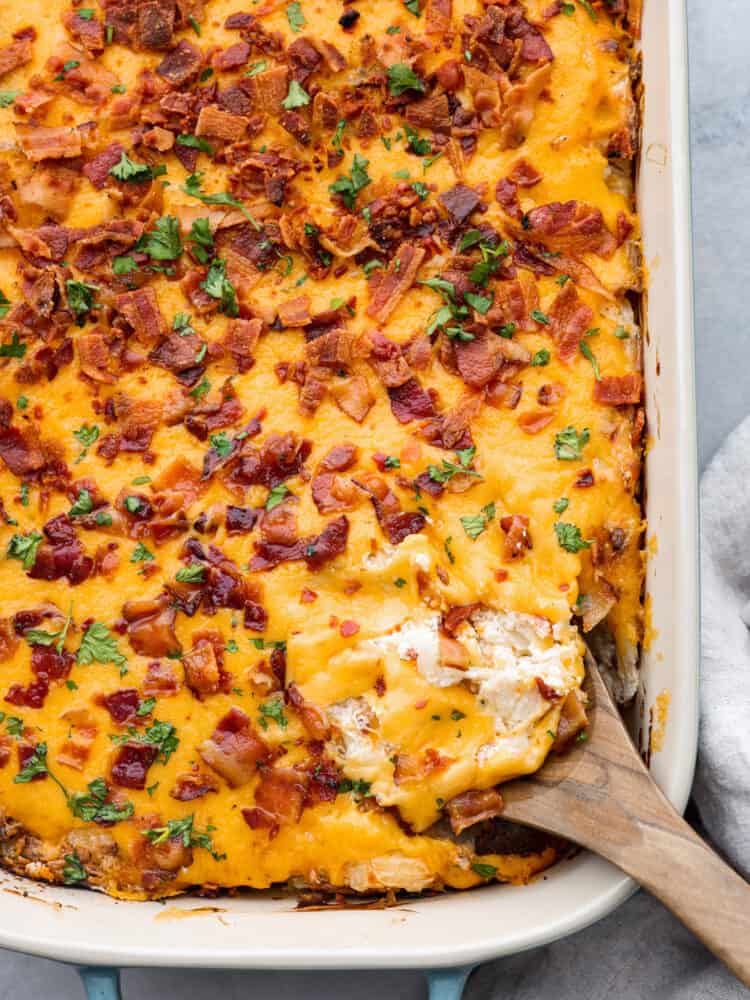 Just like the name says, these crack potatoes are so good you’ll be addicted! It’s an easy, cheesy side dish that the whole family will love. Shredded potatoes covered in a cheesy ranch sauce topped with bacon. What could be better? Top-down view of crack potatoes in a casserole dish.